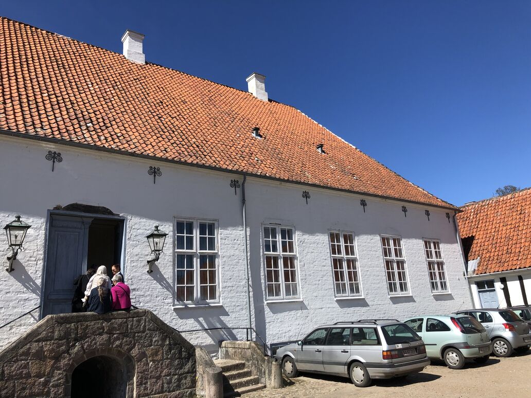 Udsnit af herregården Brobygaard, hvor en lille gruppe af mennesker er på vej ind ad dør.