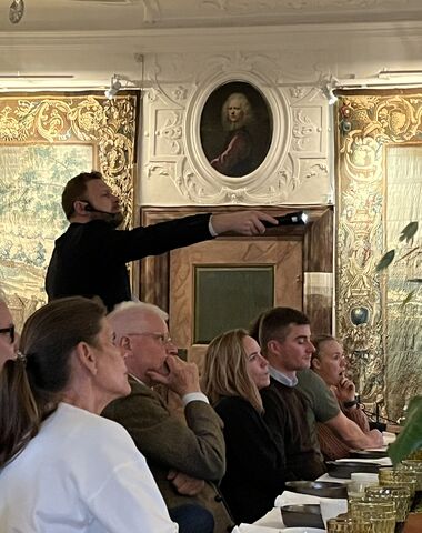 Udsnit af mand der peger og fortæller for en forsamling til arrangement i Den Store Sal på herregården Gammel Estrup