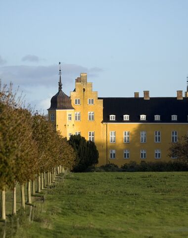 Herregården Krenkerup. Gulkalket hovedbygning med hjørnetårne og kamtakkede gavle.
