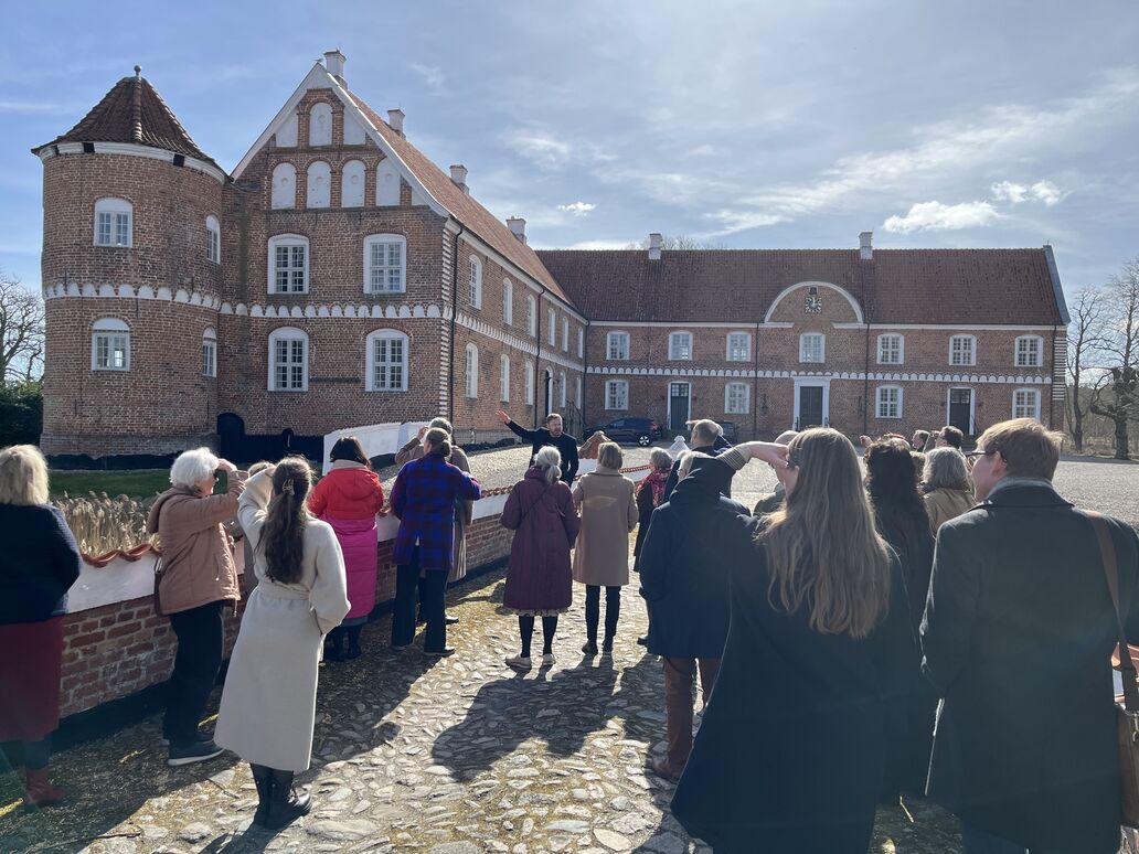 Forsamling med guide foran herregården Løvenholm.